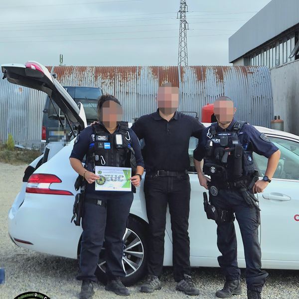Deux agents de Police Municipale en tenue d'intervention posant avec une troisième personne devant un véhicule, l'un tenant une attestation du CEUC